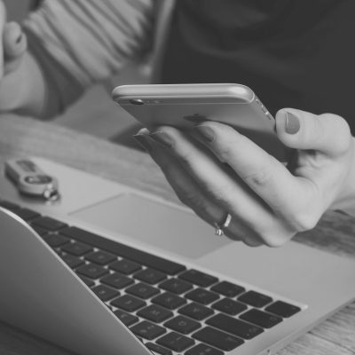 Femme à son ordinateur tenant son téléphone intelligent devant elle