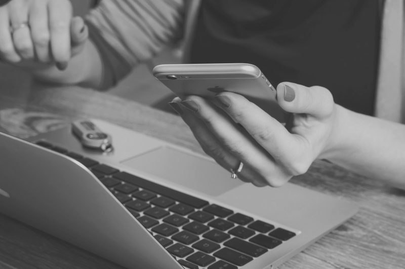 Femme à son ordinateur tenant son téléphone intelligent devant elle